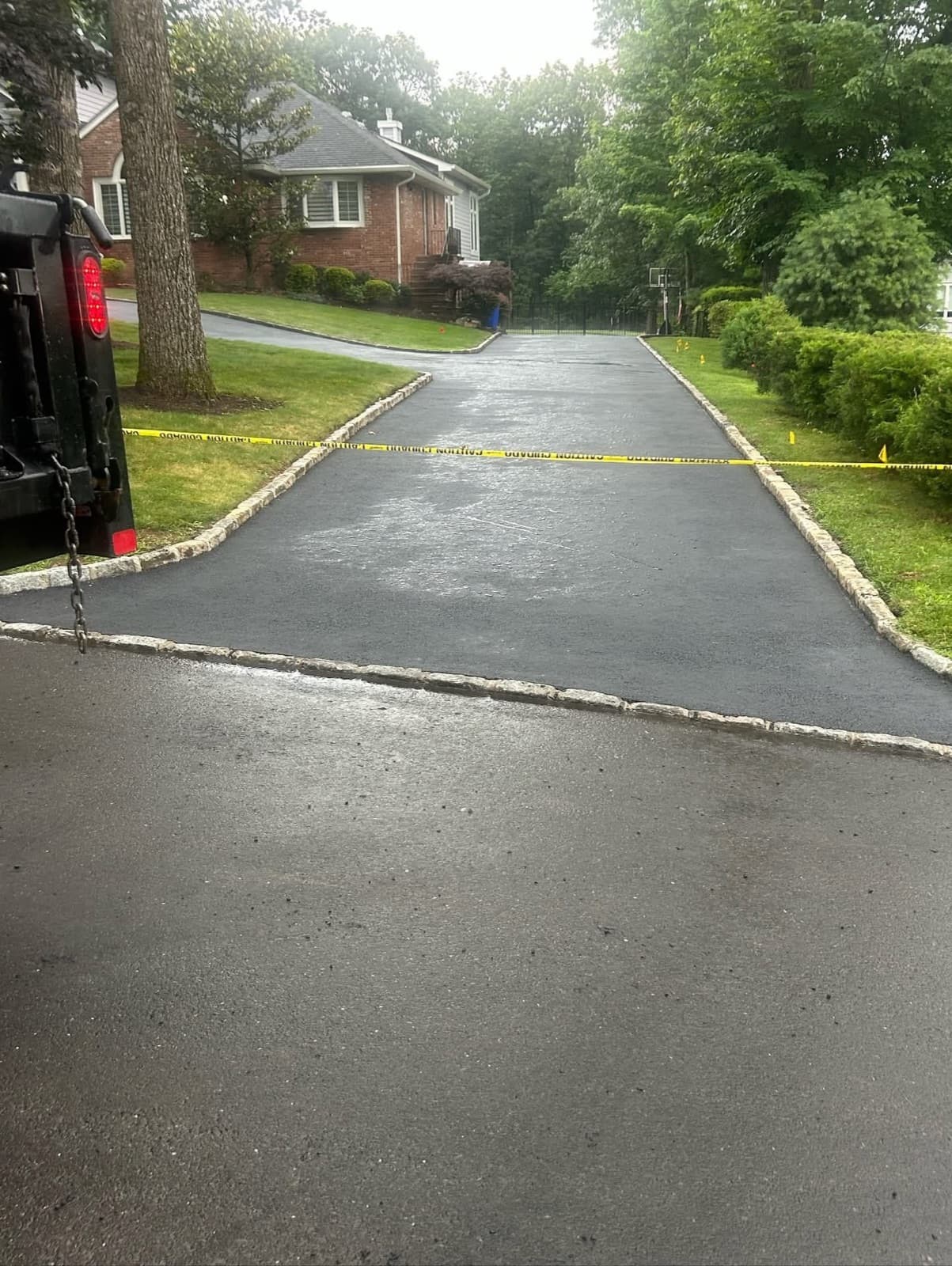 New asphalt driveway with Belgian block cobblestone edging at a brick home